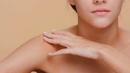 Close-up shot of young woman who gently touches her skin running hand from her shoulder along clavicles