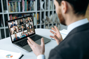 Online training, distant meeting. Caucasian businessman, sits in front of laptop screen in the...