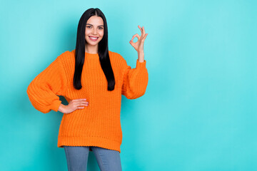 Photo of cute shiny woman wear orange sweater showing okey sign empty space isolated turquoise color background