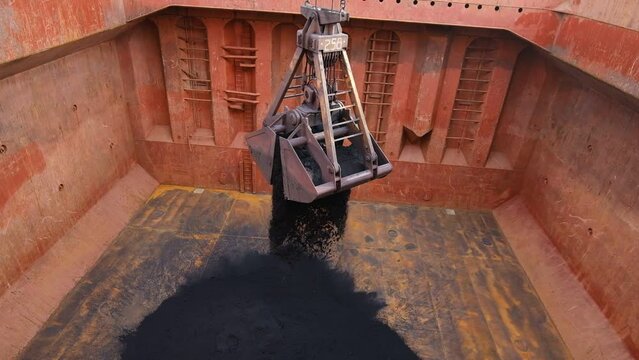 Loading of iron ore concentrate by steel grab into ship's cargo hold