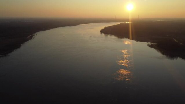 Vast river Scheldt and silhouette of buildings in horizon, aerial drone view during golden sunset