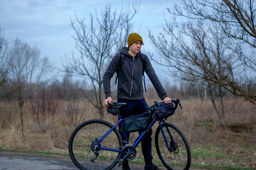 Middle-aged guy cyclist in the forest in spring in cloudy weather. Road bike. gravel bike. bike rides. travel light. healthy lifestyle