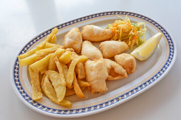 Small fried squid and fried potatoes in an oval dish.