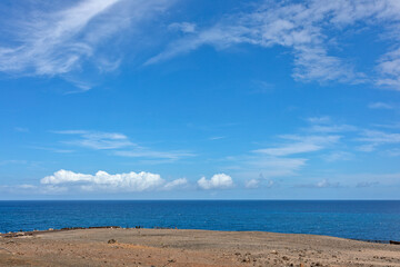 Fototapeta na wymiar View of the blue sea and sky with cirrus clouds and white cumulus clouds near the horizon.