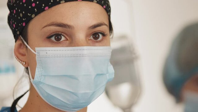 Portrait of beautiful young woman female doctor wearing medical face mask indoors in hospital. Close Up Doctor or nurse With Face Mask Preparing Surgery Intervention Medical Clinic. Medicine concept