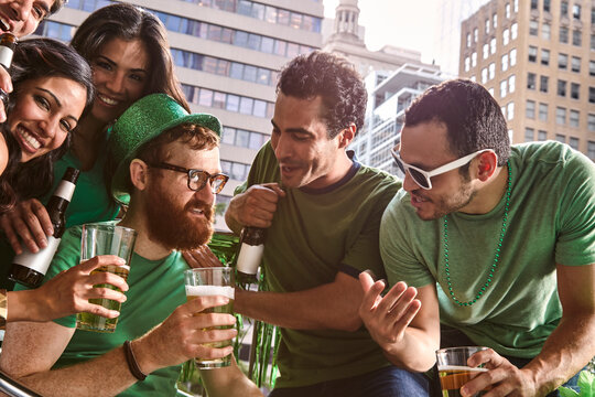 Group of diverse friends toasting while drinking beer and celebrating St Patrick's Day