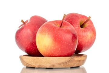 Three ripe red apples on a wooden saucer, macro, isolated on a white background.
