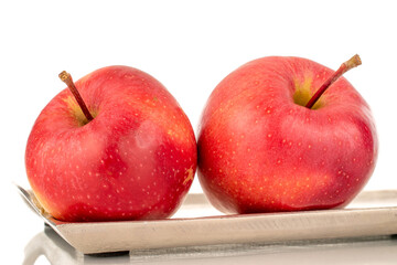 Two ripe red apples on a metal tray, macro, isolated on a white background.