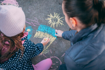 The child draws a flag of Ukraine on the asphalt with chalk. Selective focus. They don't want war....