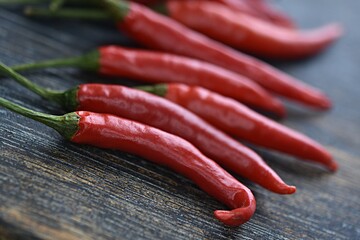 red chili peppers in a group on a dark wooden cutting board