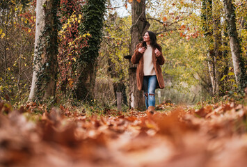 Low view of woman walking on a path full of dry leaves.