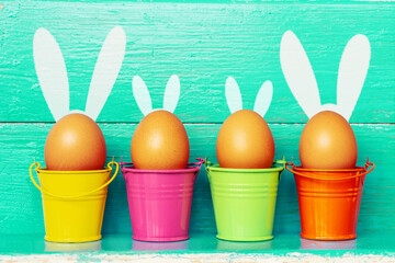 multi colors painted easter eggs in colored buckets with bunny rabbit ears. Happy Easter Card	
