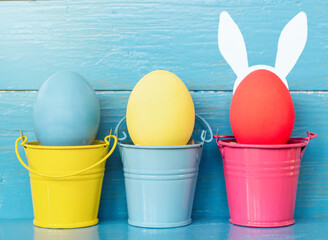 multi colors painted easter eggs in colored buckets with bunny rabbit ears. Happy Easter Card	
