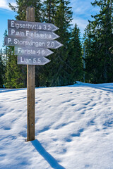 Wooden sign post with directions to destinations and distances in Bymarka nature reserve in the winter. Trondheim, Norway