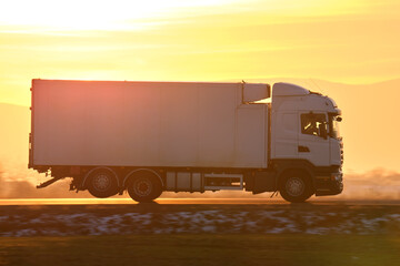 Cargo truck driving on highway hauling goods in evening. Delivery transportation and logistics...