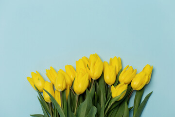 Naklejka premium Mock-up of a bouquet of yellow tulips on a blue background. Women's Day. Mothers' Day. A bouquet of flowers.