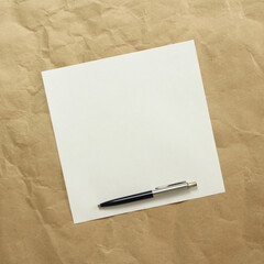 Square white empty sheet of paper with pen on a beige craft paper. Concept of analysis, study, attentive work. Stock photo with empty place for your text and design. Square image shape.