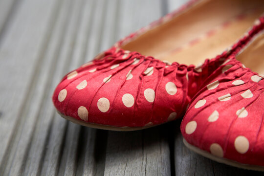 Close-up of a pair of red spotted shoes on wooden decking