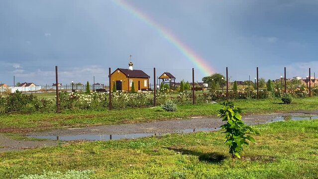 Colorful rainbow over small Russian Orthodox church as a positive symbol of change, faith and divine miracles. natural phenomenon after the rain. Blessing of temple.