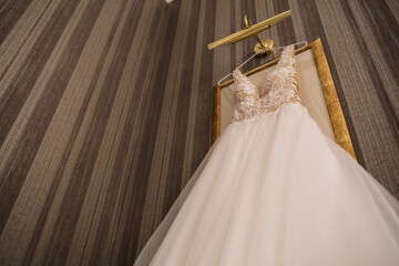 Wedding dress hanging against a wall background in the room. Close up.