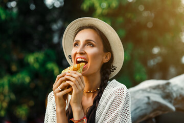 Vegan girl, healthy appearance, holds in her hands and eats a natural, meat-free burger, colored bun, tofu, soy meat, chickpeas. Tropical island Thailand, Bali