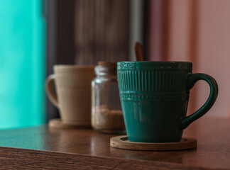Vintage pastel aqua and beige coffee or tea mugs by the window on a rustic wooden tabletop. Hot drinks.