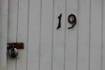Old wooden door and latch with the door number of nineteen on it