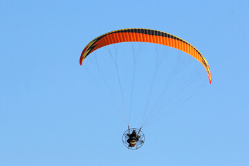 Paramotor pilot flying in a blue sky	