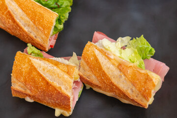 delicious ham sandwich with cheese and lettuce, on a black plate, cooked in a restaurant