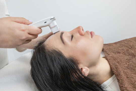 Dermatologist performing a facial analysis and diagnosis on a beautiful woman lying down.Detailed scanning of skin hydration, sebum, acne, wrinkles, sensitivity and melanin. Beauty concept and trend.