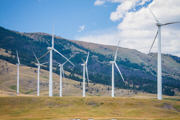 Wind farm with beautiful mountains in the background. The wind turbines face multiple directions...