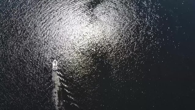 Luftaufnahme von Motorboot fahrend auf Wasser mit Wellen zwischen Inseln mit B&auml;umen in Schweden auf See bei Sonne per Drohne gefilmt