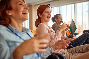 Two cheerful female colleagues having fun during a business lecture in the conference room....