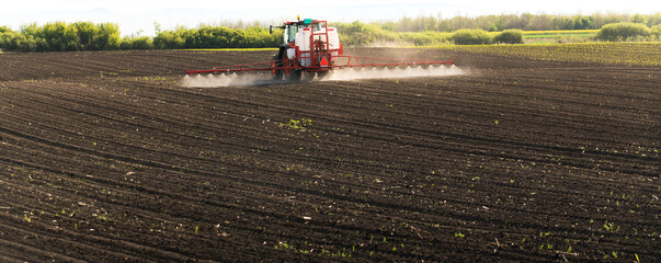 Tractor spraying land in sunset.