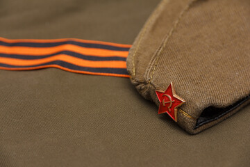 Headdress of the Soviet Army Pilotka on the background of the St. George ribbon and army fabric.