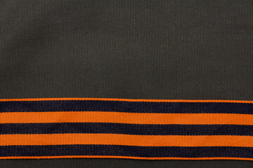 St. George's ribbon on a green fabric background. Isolated St. George Ribbon