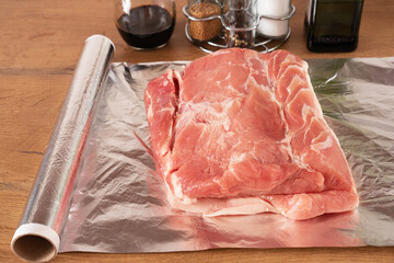 Piece of raw meat on aluminium foil sheet for baking. Cooking pork.
