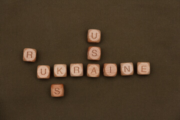 Wooden cubes collect the word Ukraine Rus USA on the background of green army fabric. Concept of several words