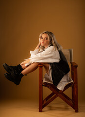 Posing on the chair alone in studio on yellow background while enjoying her time