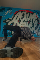 Trendy young man dancer dancing in front of graffiti.