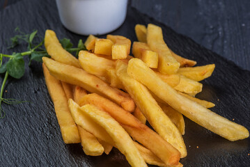 French fries with garlic sauce on a black slate tray