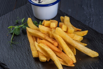 French fries with garlic sauce on a black slate tray