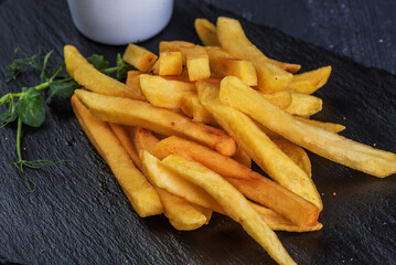 French fries with garlic sauce on a black slate tray