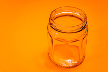 Empty hexagonal glass flask isolated on orange bottom. Kitchen utensils.