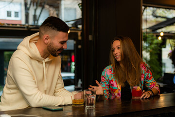 The guy is flirting with the girl while talking and drinking