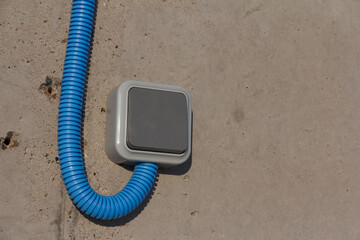 Industrial Electric Switches with protected cable on a concrete wall. Industrial lighting.