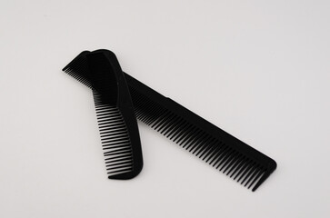 Two hair combs, with a large one laying on top of a smaller one.