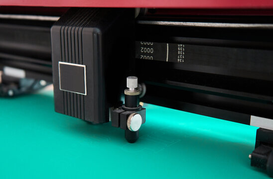 Cutting plotter close-up. The process of cutting a green vinyl film.