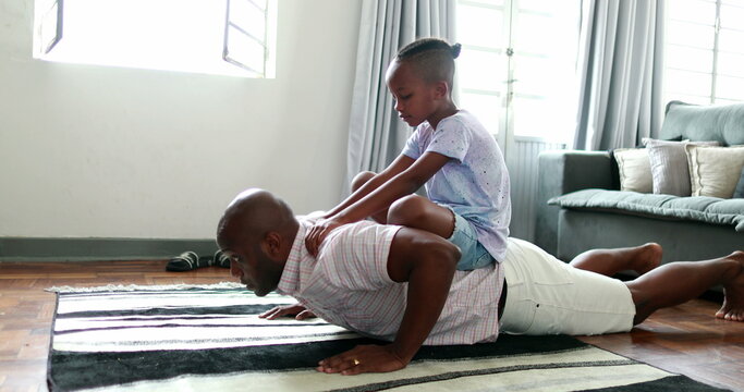 Father and child bonding together, dad doing push-ups with son in back