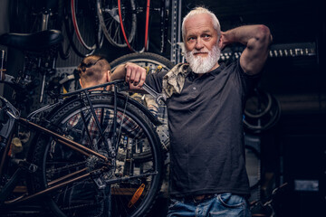 Fototapeta na wymiar Aged man mechanic repairing bicycles indoors his workshop